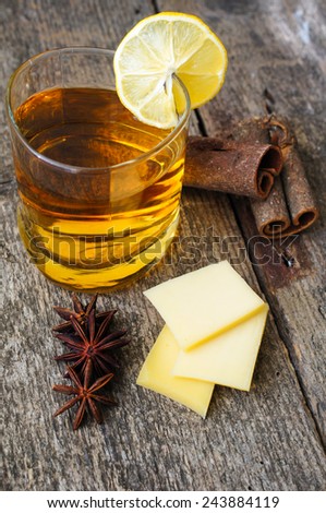 Glass of brandy with lemon, spices and cheese on the old wooden table