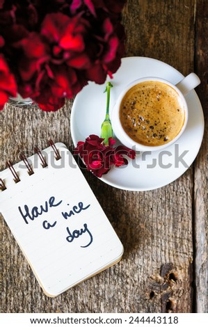 Cup of coffee and red cloves flowers in a vase with good morning note