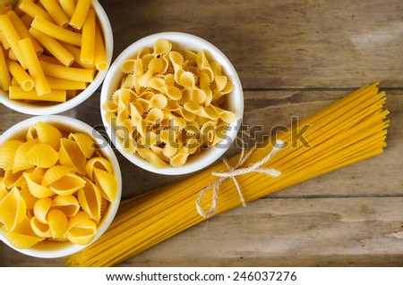 Different kinds of italian pasta, like a fusilli, farfalle, spaghetti and penne pasta
