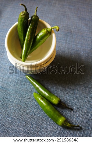 A pile of green banana peppers on the old wooden table