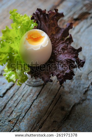 Soft boiled egg in egg cup and served with lettuce leaves