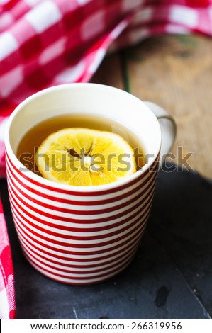 Red striped cup of tea with lemon and red napkin