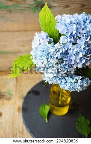 Hydrangea flowers in a vase on the old wooden table, selective focus