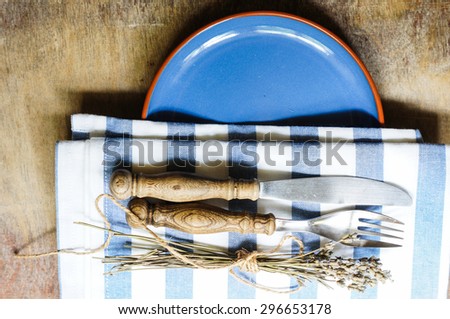 Rustic Table Setting with napkin, silverware and dry lavendre lowers on old wooden table
