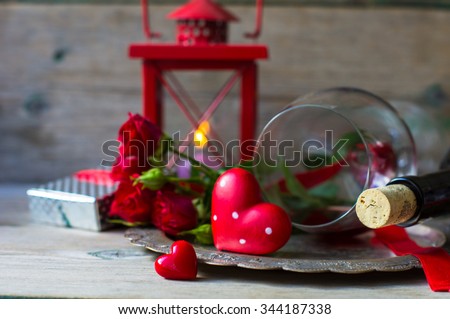 Table setting for St. Valentines day with glasses of red wine, present box and red roses  in rustic style