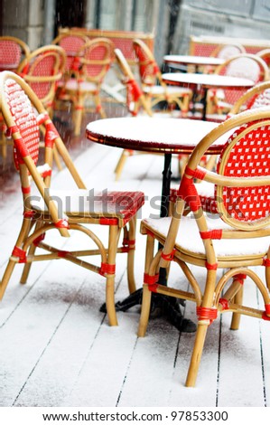 Rare snowy and cold day in Tbilisi. Street red cafe table and chairs covered with snow