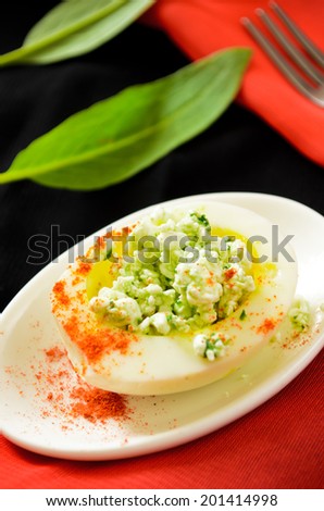 eggs with cottage cheese, wild leek and paprika on black background