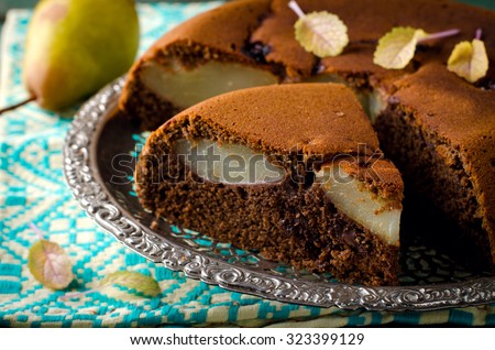 piece of homemade chocolate cake with pears and chocolate drops on a rustic background