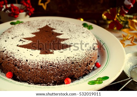 Traditional Homemade chocolate Christmas cake sprinkled with sugar powder, new year tree decoration with snow