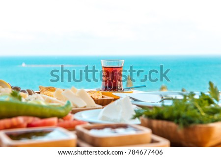 Turkish tea with breakfast on the table in front of sea background landscape at Summer season. Turkish or Greek Breakfast at seaside. This turkish tea is red. Holiday and vacation in Turkey or Greece