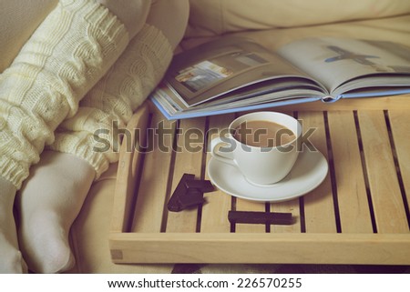 Cozy Winter: woman in warm socks with coffee and a book. Retro toning