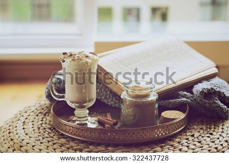 Cozy morning: cocoa cream and a book by the window in retro style