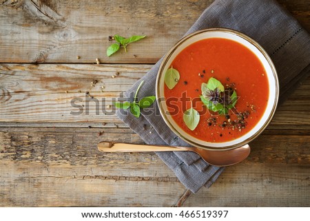 Tomato soup on wooden table, top view