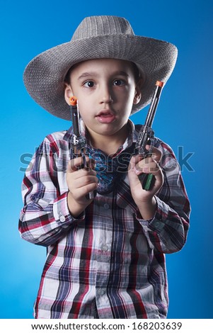 Studio shot of masked little cowboy with revolver toy.