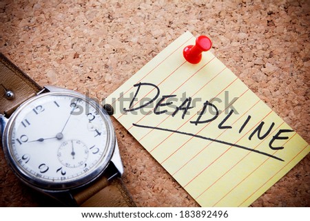 Deadline word written on a post note and hanged on the cork-board with an old hand watch.