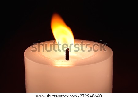 Candle on the dark background - symbol of sadness or romance.