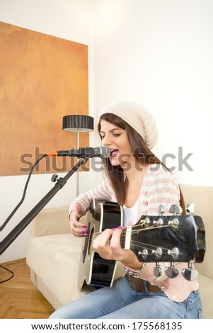 pretty girl singing and playing guitar on the couch by the lamp