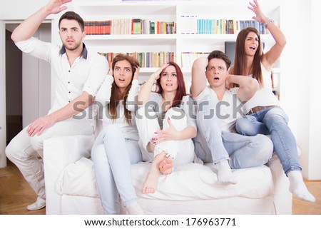 group of friends watching bad game on tv with expression because their team lost