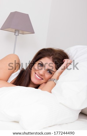 beautiful young woman on the bed on white pillow smiling