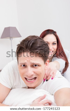 scared afraid man in white t-shirt trying to escape from woman in bedroom