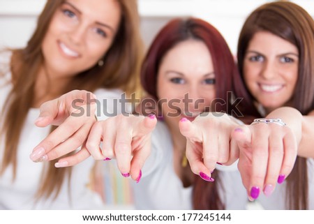 beautiful happy girls pointing their fingers at you with focus on fingers