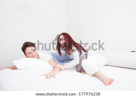 pretty young man and woman in pillow fight smiling