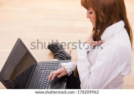 young business woman sitting on the floor typing on laptop keyboard