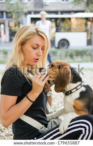 beautiful young woman holding and feeding beagle puppy dog