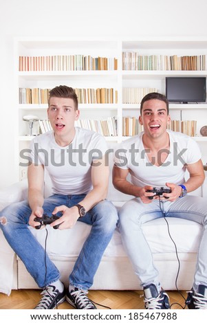 two competitive friends at home playing video games with controllers
