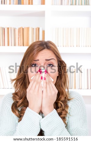 beautiful sick woman with cold and virus sneezing into tissue