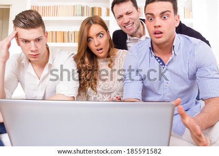 shocked and frustrated casual group of friends sitting on couch looking at laptop, pissed off friends, cheering on computer