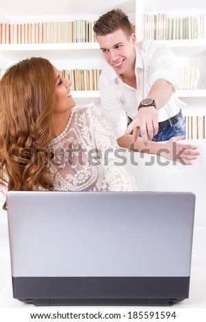 casual young man showing something to his pretty wife on a screen in their living room
