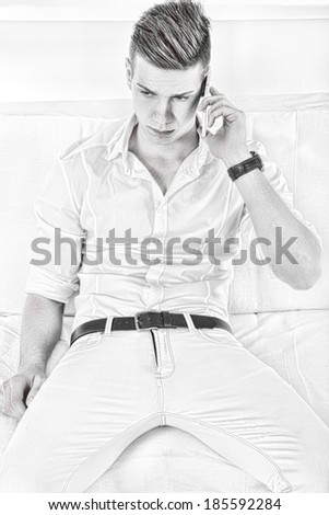 worried sad young casual man talking on the phone at home in black and white