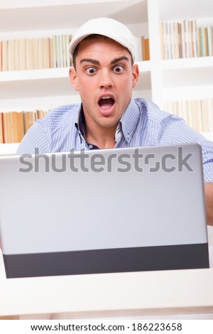 shocked business man wearing cap looking at his monitor with open mouth yelling having problem
