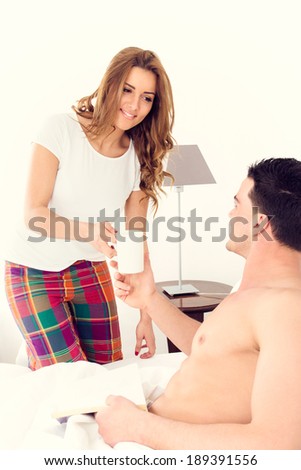 caucasian woman carrying coffee to her boyfriend in bed smiling