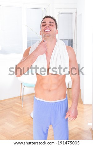 sexy man in pajamas shaving beard with razor in the morning smiling man shaving with towel around neck
