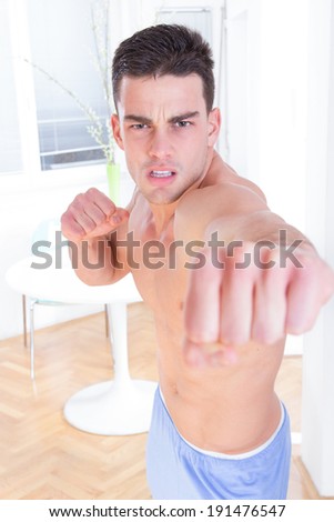 angry man hitting into camera with clenched fist, handsome shirtless fighter punching with fists