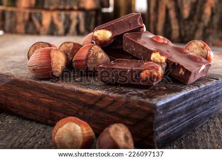 Pile of delicious chocolate bars with whole nuts on wood, Warm composition of chocolate pieces with hazelnuts