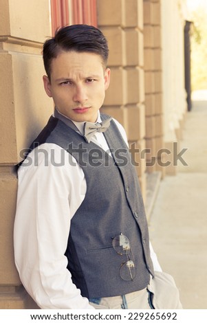 handsome young retro male model posing outdoors by the wall
