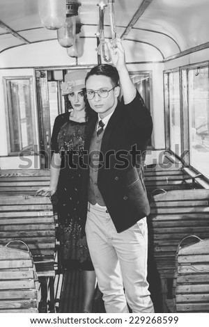 old time modern man with glasses in suit in a wagon train with a woman behind him, vintage retro fashion photo