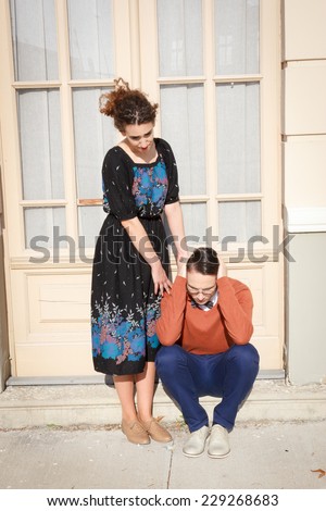 pretty young woman comforting depressed man in front of the house in the stairwell