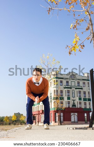 young handsome casual man standing or squatting on the sidewalk in  old city and looking at camera , retro vintage fashion composition