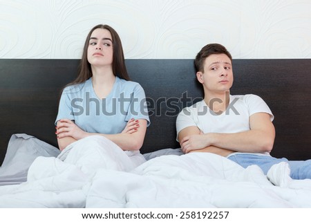 Portrait of unhappy and annoyed young caucasian couple after quarreling in bedroom under stress. Upset man and woman secretly watching each other because mistake, relationship and marriage sex problem