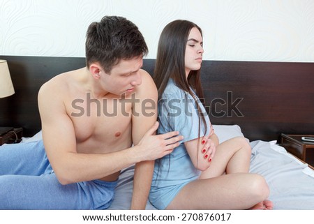 Angry half naked couple siting back to back in bedroom, having relationship problems. Sad man asking his wife to forgive him mistake, marital difficulties. After argue upset time. Domestic atmosphere.