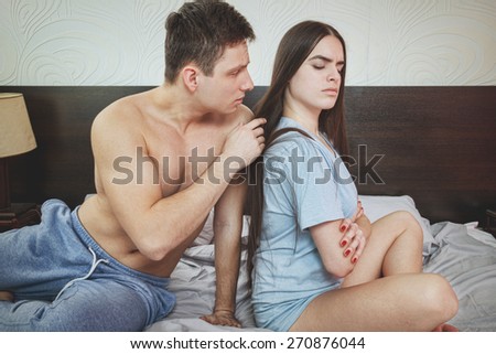 Angry half naked couple siting back to back in bedroom, having relationship problems. Sad man beging his wife to forgive him mistake, marital difficulties. After argue upset time. Domestic atmosphere.