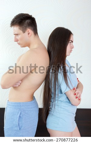 Young angry half naked couple standing back to back in bedroom, having relationship problems. Unhappy man and woman with marital difficulties situations. After argue upset time. Domestic atmosphere.