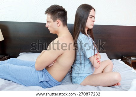 Young angry half naked couple siting back to back in bedroom, having relationship problems. Unhappy man and woman with marital difficulties situations. After argue upset time. Domestic atmosphere.