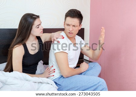 Not in Good Terms Young Couple on Bed. Angry and pissed off man sulking while his woman is explaining herself during fight in bedroom. Understanding and consolation after stubborn quarrel.