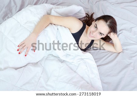 Beautiful sexy young passionate smiling woman lying and posing in bedroom. Domestic atmosphere photo. View from above or top.