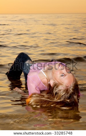 Sexy woman posing in the sea in wet clothes.